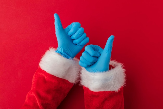 Photo santa hands wearing blue ppe protective gloves making thumbs up sign