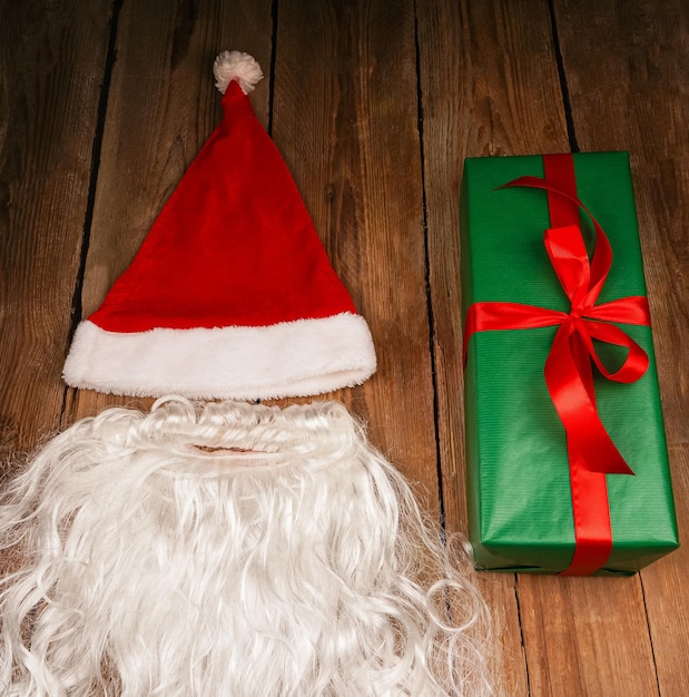 Photo santa hat and beard on a wooden background symbolism of new year's holidays christmas and new year concept change of clothes change of image