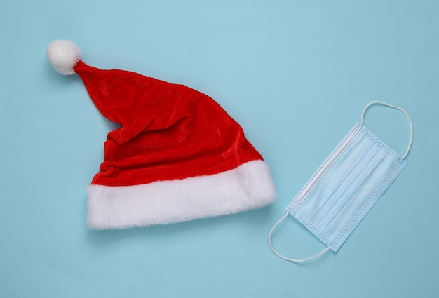 Foto cappello da babbo natale e maschera medica su sfondo blu