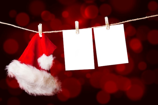 Santa hat with papers hanging on rope against red background