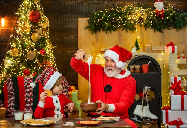 Santa helper cute little child boy and daddy make gingerbread cookies near christmas tree merry chri...