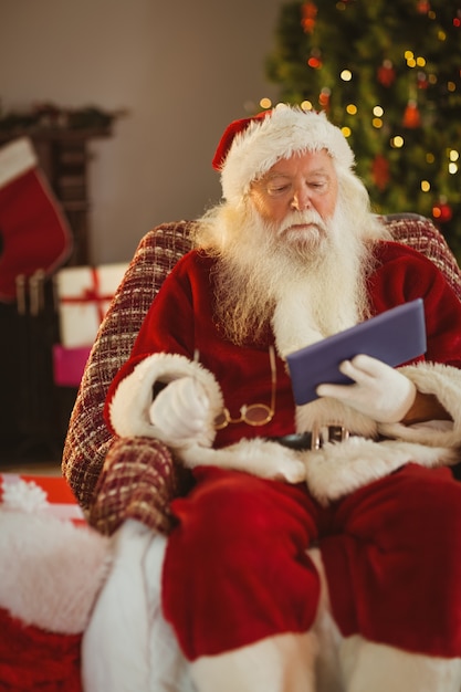 Santa holding his glasses and using tablet