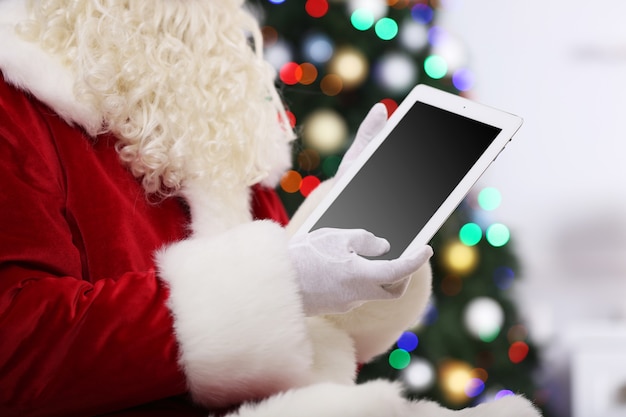 Santa holding tablet on Christmas tree