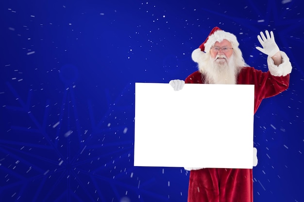 Santa holds a sign and is waving against blue snowflake background