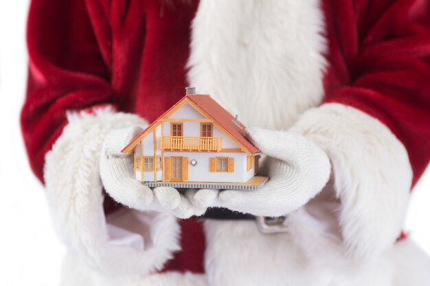 Санта держит в руках крошечный дом