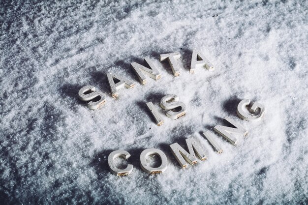 Photo santa is coming writing on white snowy background.