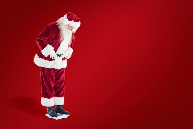 Santa looks down to personal scales against red background