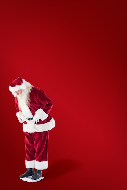 Santa looks down to personal scales against red background