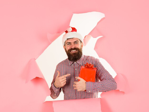 Santa man toont met vinger op geschenkdoos nieuwjaar winter kerstcadeautjes bebaarde man in kerstmuts
