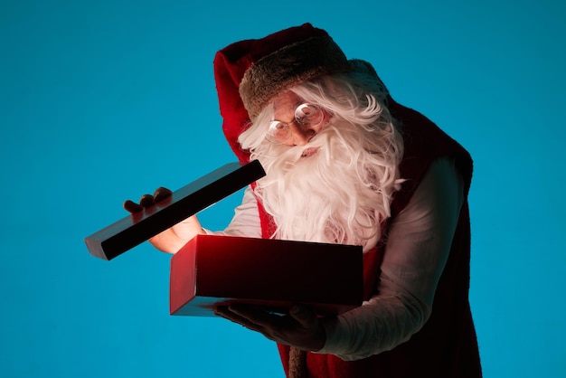 Santa opens a magic box with a gift on a clean blue background christmas gifts