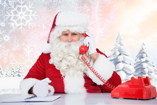 Santa on the phone against snowy landscape with fir trees