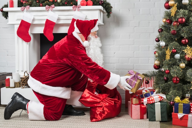 Santa putting presents under Christmas tree