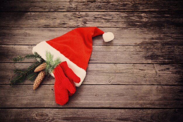 Santa's hat and red mitten on old wooden background