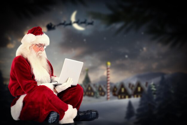 Santa sits and uses a laptop against santa delivery presents to village