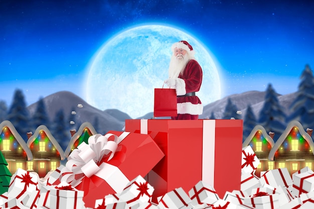 Photo santa standing in large gift against quaint town with bright moon