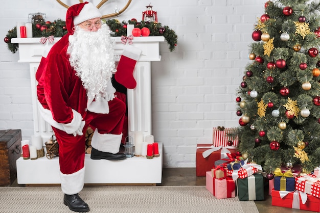 Santa standing near white decorated fireplace