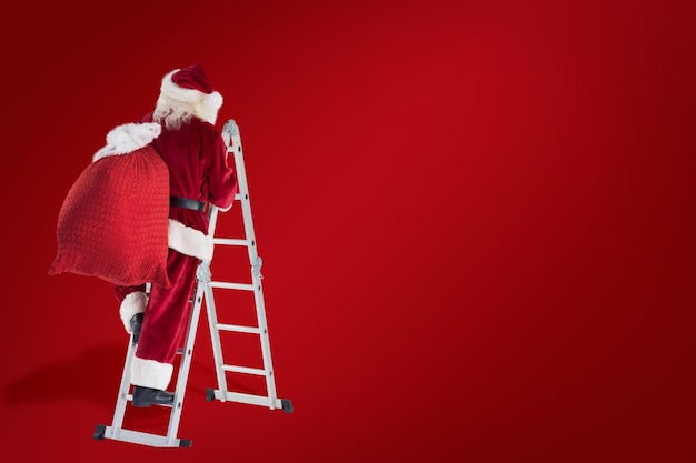 Santa steps up a ladder against red background