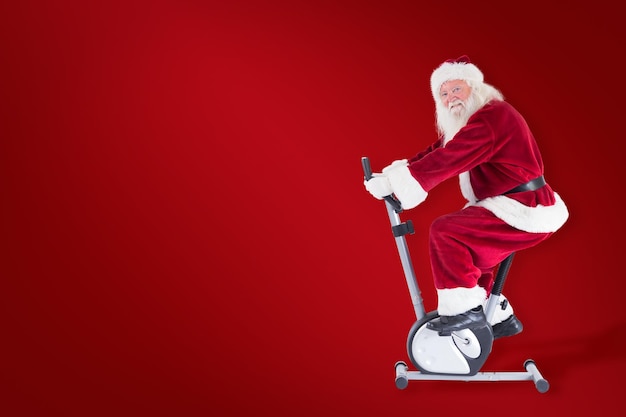 Santa uses a home trainer against red background