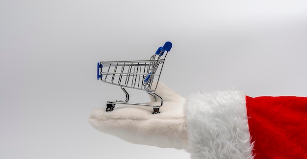 Santa39s hand holds a miniature supermarket cart in the palm