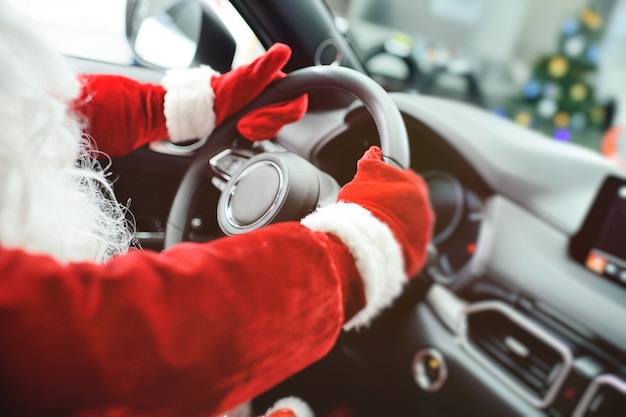 Santas hands in red gloves holding the steering wheel of a car