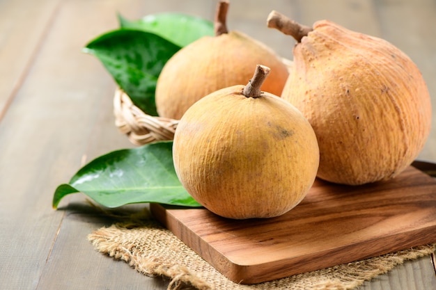 Santol fruits in bamboo basket on wood background, Santol has sour taste and the middle of santol is sweeter. It is very famous fruit of Lopburi Province. THAILAND