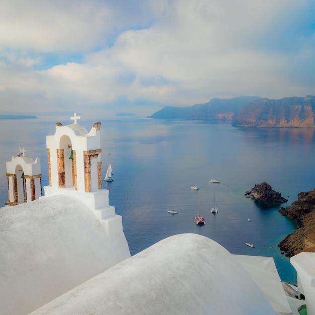 写真 サントリーニ島ギリシャ サントリーニ島の有名な建築の概念構成白い鐘のアーチとボートのある青い海の眺めサントリーニ島ギリシャ ヨーロッパ