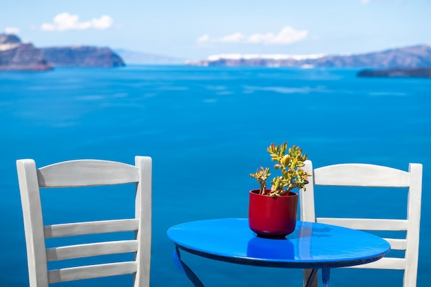 Foto isola di santorini grecia due sedie bianche con tavolo blu sulla terrazza con vista mare