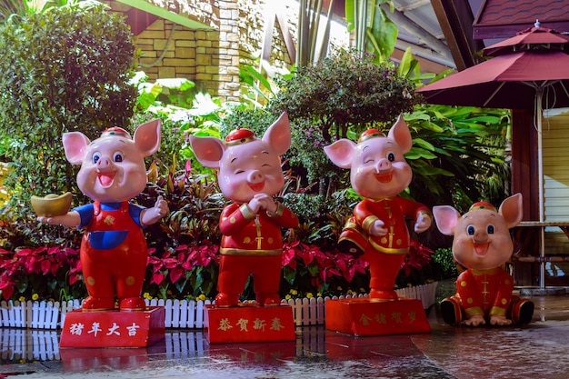 Sanya, Hainan, China - February 20, 2020: Colorful statues of four little pigs on the street of Sanya at cloudy day.