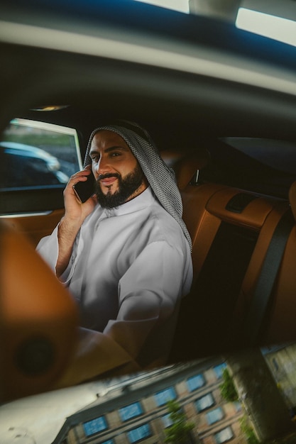 Saoedische man zit in een auto en praat aan de telefoon