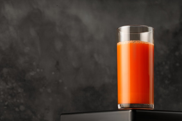 Foto sap van wortel in glas vers geperst sap op donkere achtergrond voor verpakking en menu