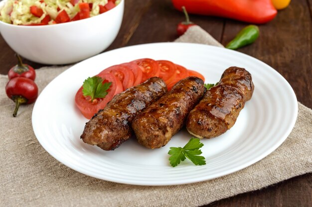 Sappige gegrilde broodjes gehakt omwikkeld met spek met verse tomaat