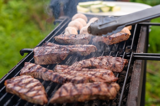 Sappige gemarmerde biefstukken en champignonhelften worden gebakken op een houtskoolgrill