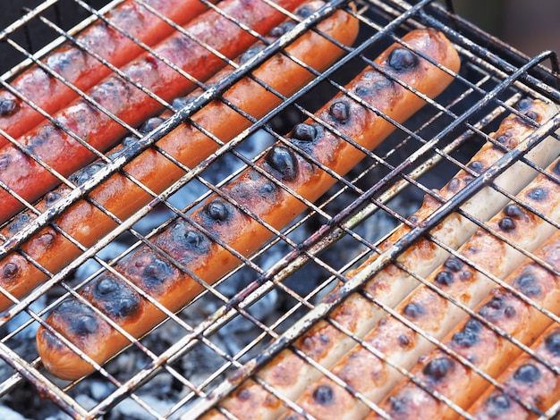 Foto sappige heerlijke worstjes op de grill worden gebakken in de grill op de kolen