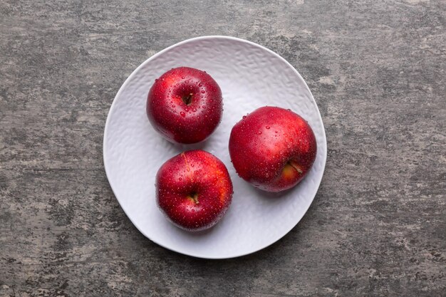 Sappige rode appels in een kom of bord op het tafelblad. Ruimte kopiëren.