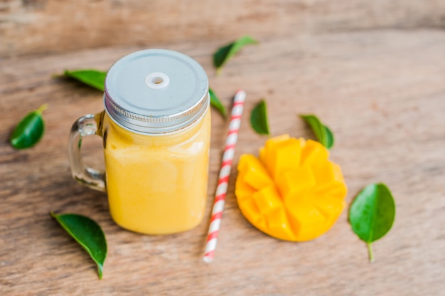 Sappige smoothie van mango in glazen pot met gestreept rood rietje