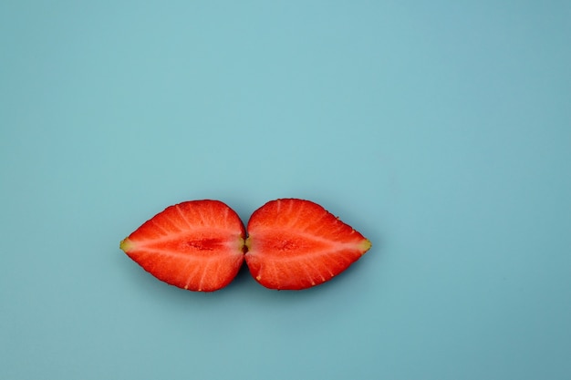 Sappige verse aardbeien verdeeld in twee helften op een blauwe achtergrond