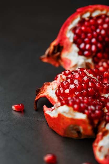 Sappige zaden van vers fruit van de geopende granaatappel op een zwart close-up als achtergrond.