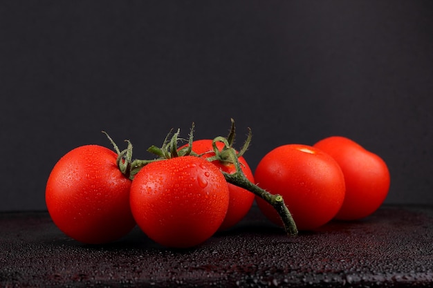 Sappige zoete rode tomaten op een zwarte achtergrond Gezonde voeding concept Close-up