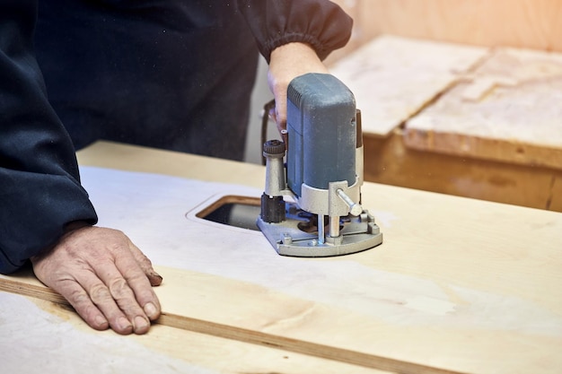 Sarpenter werken met freesmachine Schrijnwerkerij houtbewerking en meubels maken professionele timmerman snijden hout in timmerwerk workshop industrieel concept