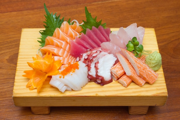 Foto sashimi (cibo giapponese). frutti di mare crudi affettati sul piatto di legno.
