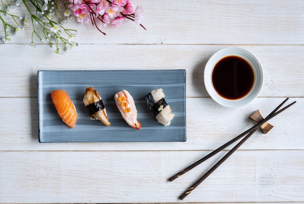 Набор суши сашими с соевым соусом на белом деревянном столе, вид сверху