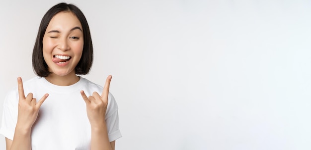 Sassy asian girl shouting enjoying concert or festival showing rock on heavy metal sign having fun s