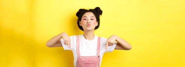 生意気なアジアの 10 代の女の子は、唇をすぼめ、指を下に向けて、下部の広告 sta を見てください