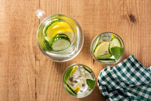 Sassy water or water with cucumber and lemon on wooden table