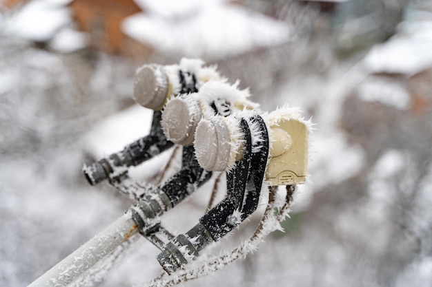 Satellietschotel in sneeuw Satellietschotel bevroren hangend aan de muur van het huisje in een besneeuwde winter buiten