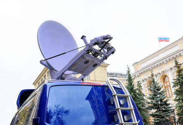 Satellietschotel op het dak van het autoregeringsgebouw met een vlag op de achtergrond