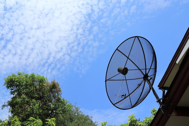 푸른 하늘 흰 구름과 여름 시간에 녹색 나무와 지붕에 위성 접시 기술과 자연