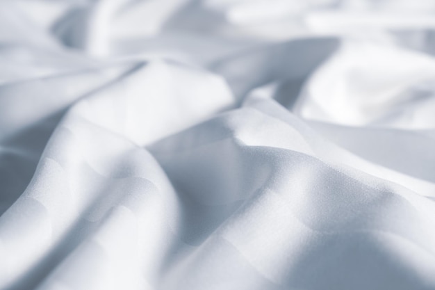 Photo satin crumpled fabric of light cold blue color top view natural bed linen sheets abstract background of luxury fabric wavy folds