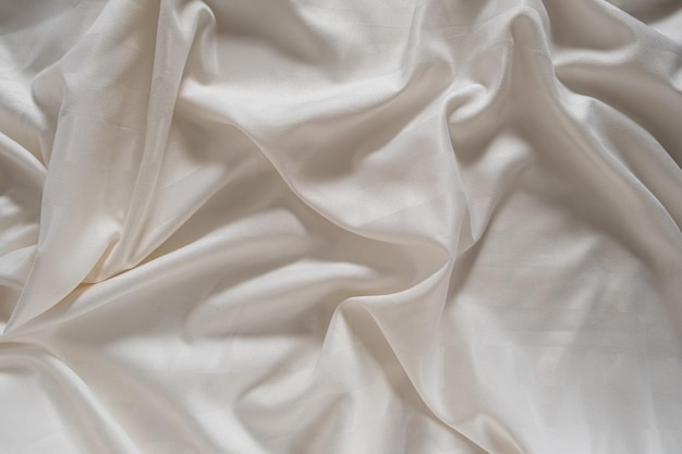 Satin crumpled fabric of light milky color top view