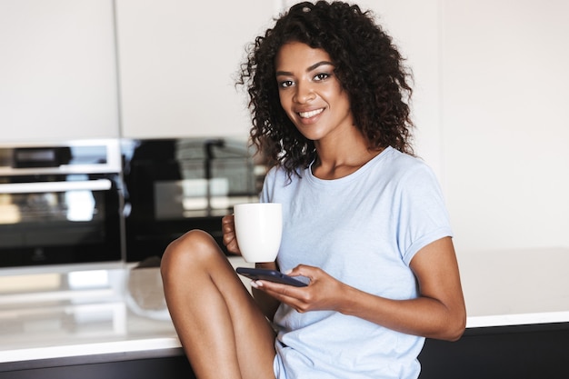 Satisfied african woman using mobile phone